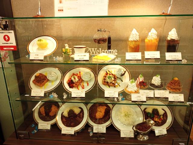Food samples such as curry and waffles displayed in the showcase at Maruzen Cafe
